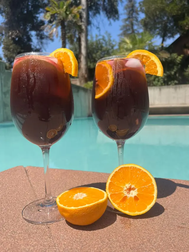 Dos copas de La Colora con naranja junto a la piscina